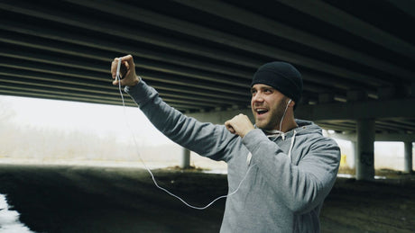 Man in beanie and hoodie singing into phone