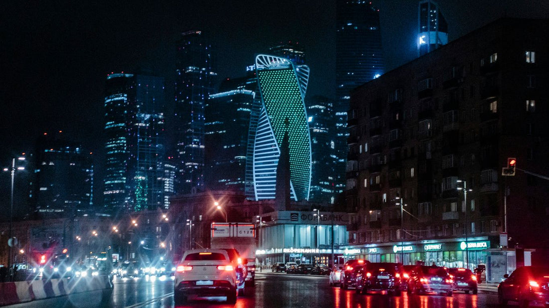 different vehicles on road viewing city with high-rise building during night time