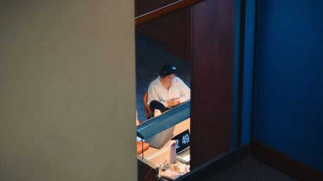 Person wearing a baseball cap at a desk.