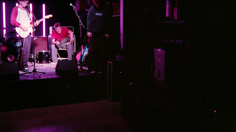 Band performing on a dimly lit stage with purple lights.